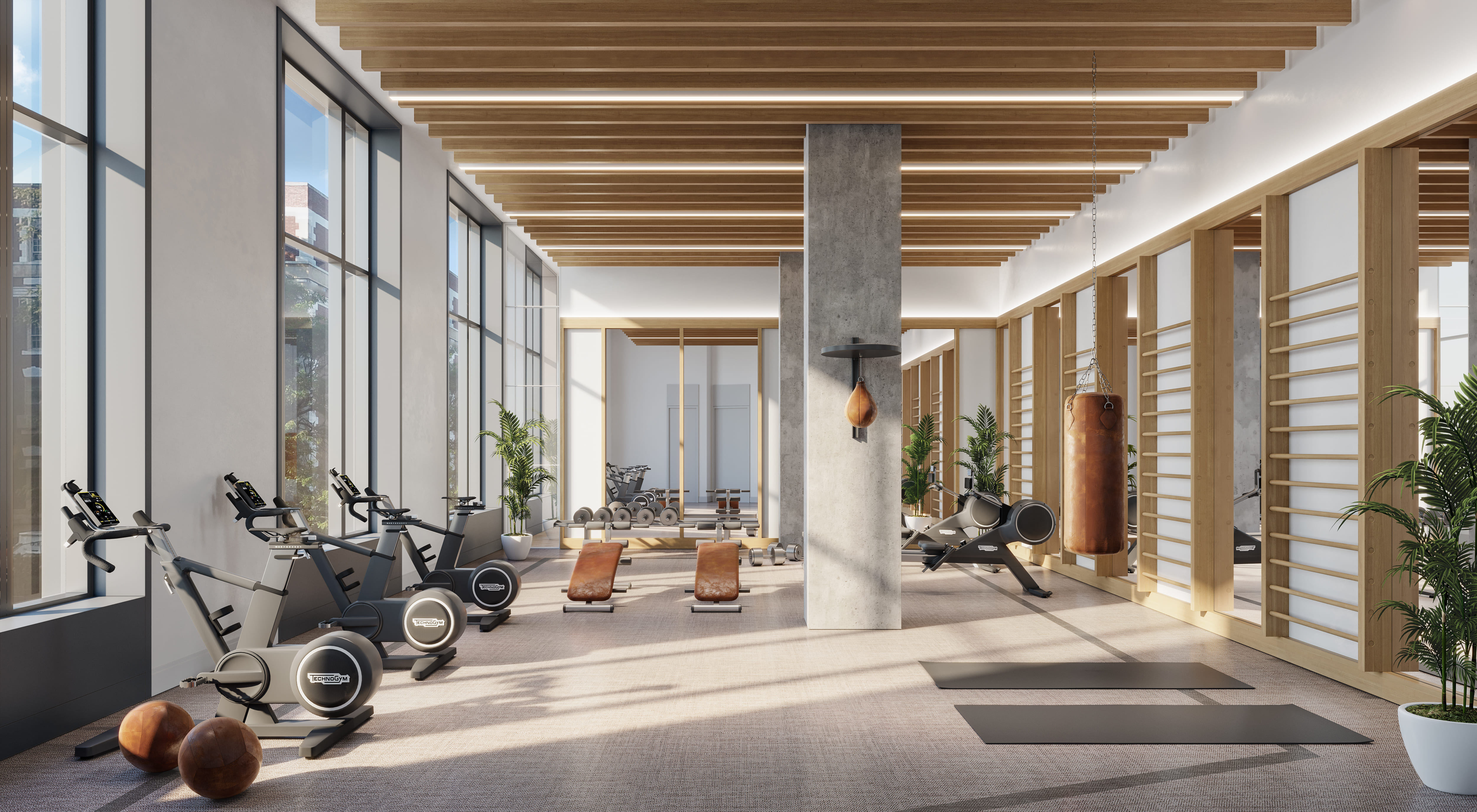 Indoor gym at NOVA LIC condos for sale. Open area surrounded by gym equipment with sun coming through windows.